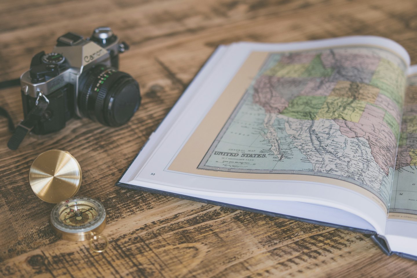 Mappa vintage, macchina fotografica e bussola su un tavolo di legno.